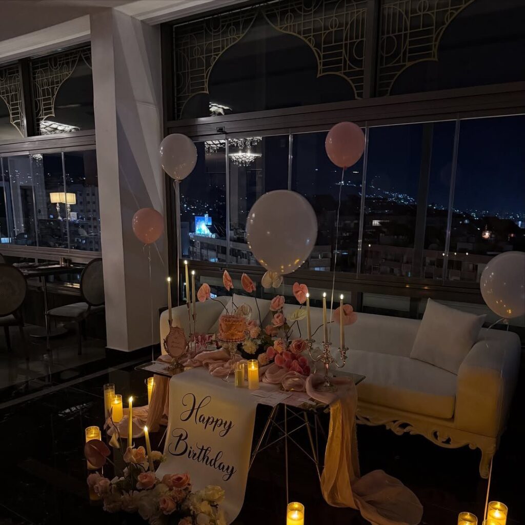 Birthday party setup with balloons and candles in a city view room