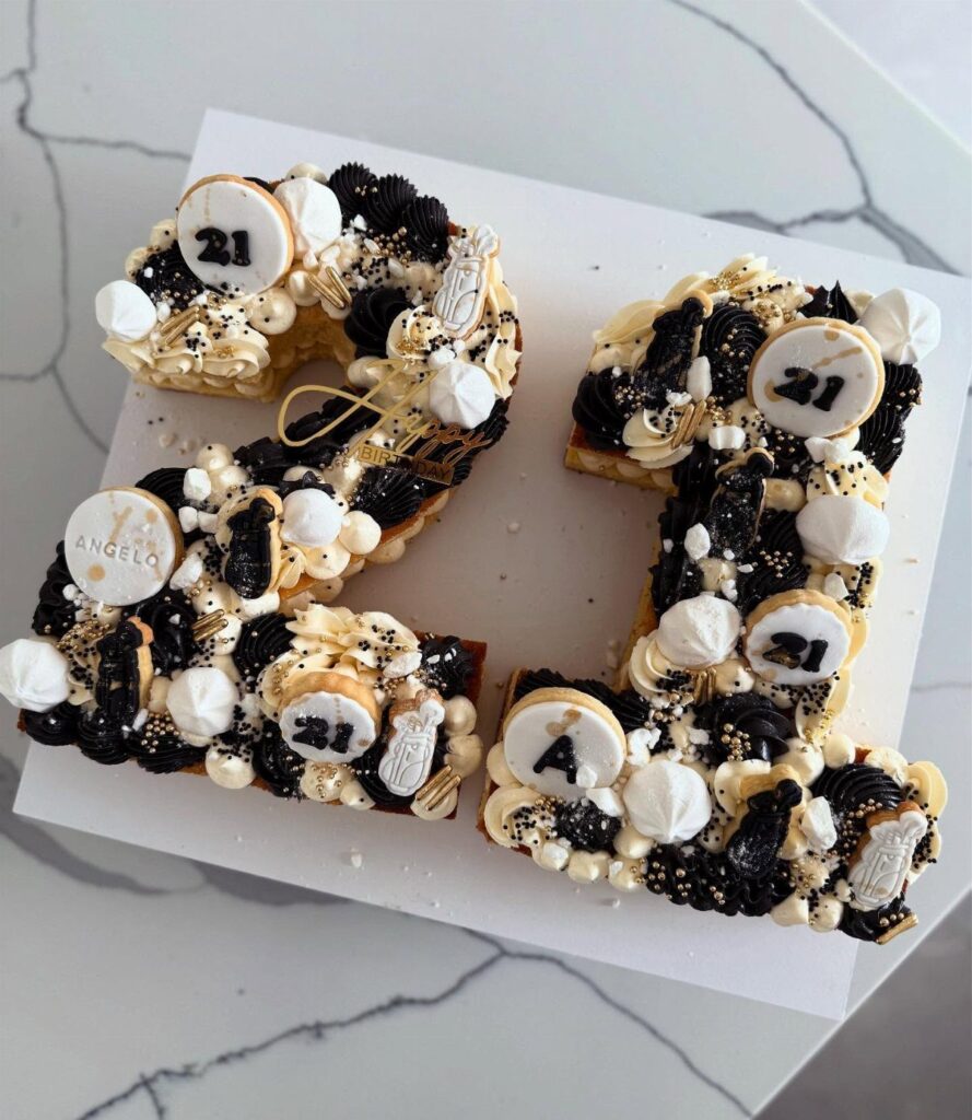 Number 21 cookie cake decorated with black and white frosting and gold sprinkles.