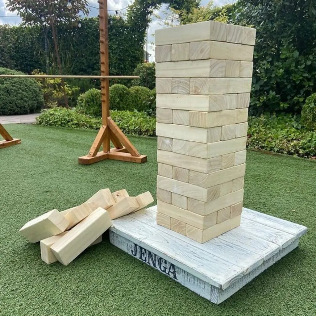 Giant Jenga tower of oversized wooden blocks on a white base in a garden