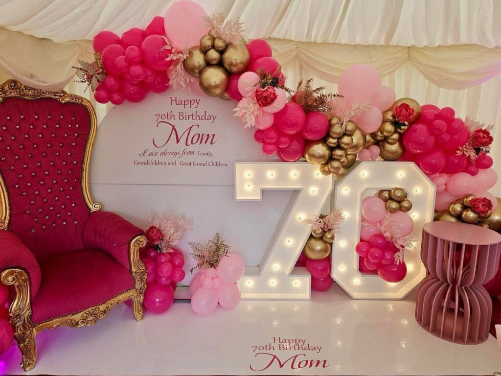 Magenta velvet chair and glowing number 70 with pink and gold balloons