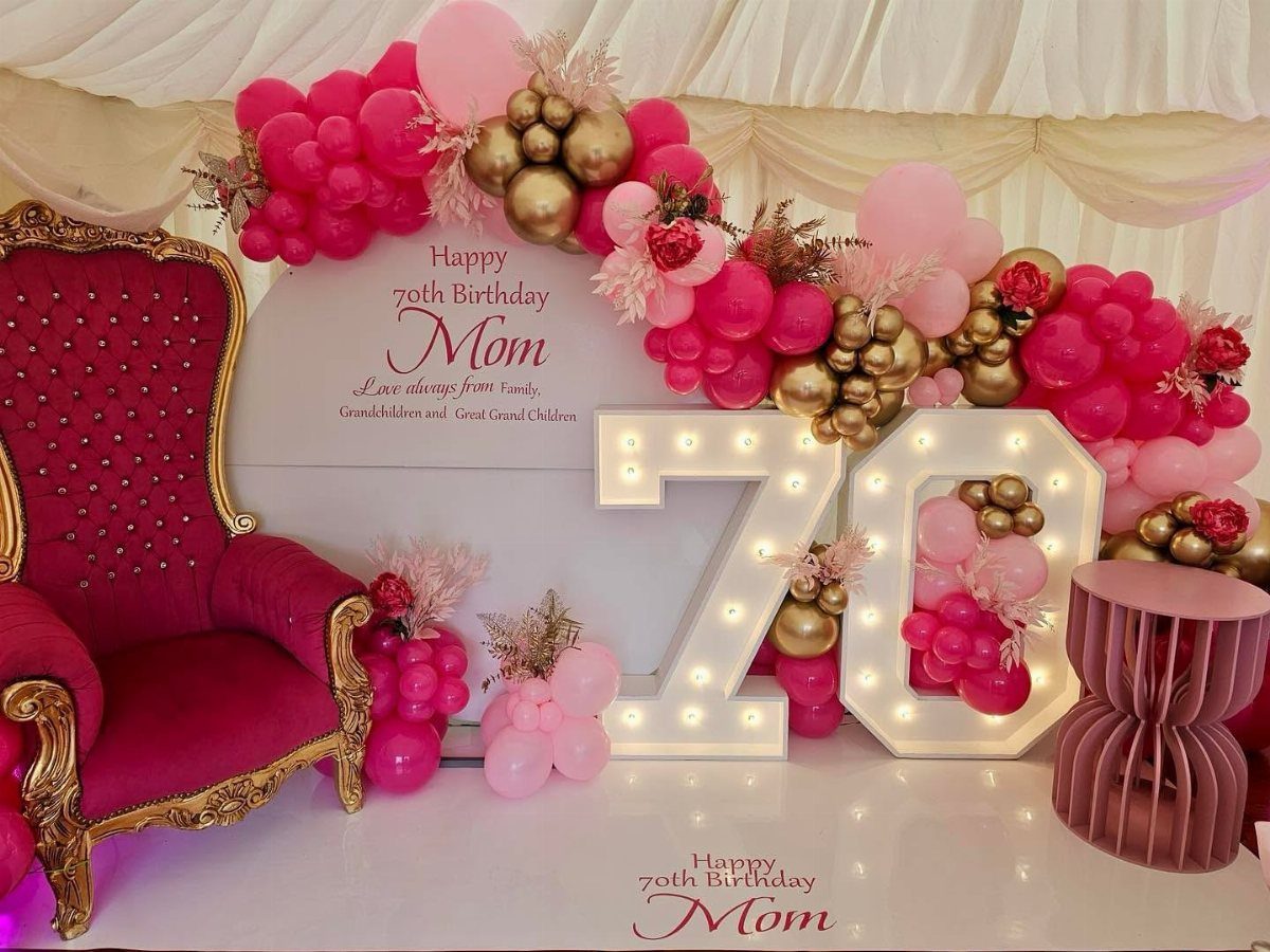 Magenta velvet chair and glowing number 70 with pink and gold balloons