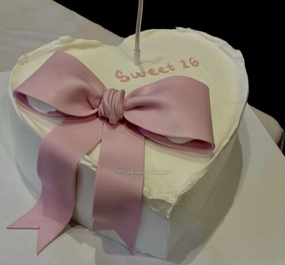 Heart-shaped white cake with a large pink bow and Sweet 16 lettering