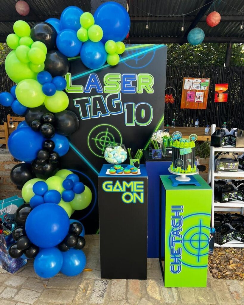 Laser tag themed birthday party setup with blue and green balloons and cake.