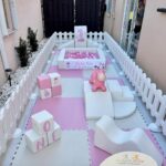 Baby party setup with pink foam mats, ball pit, and white picket fence.