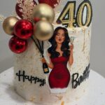 White birthday cake with gold flakes, red baubles, and a 40 topper.