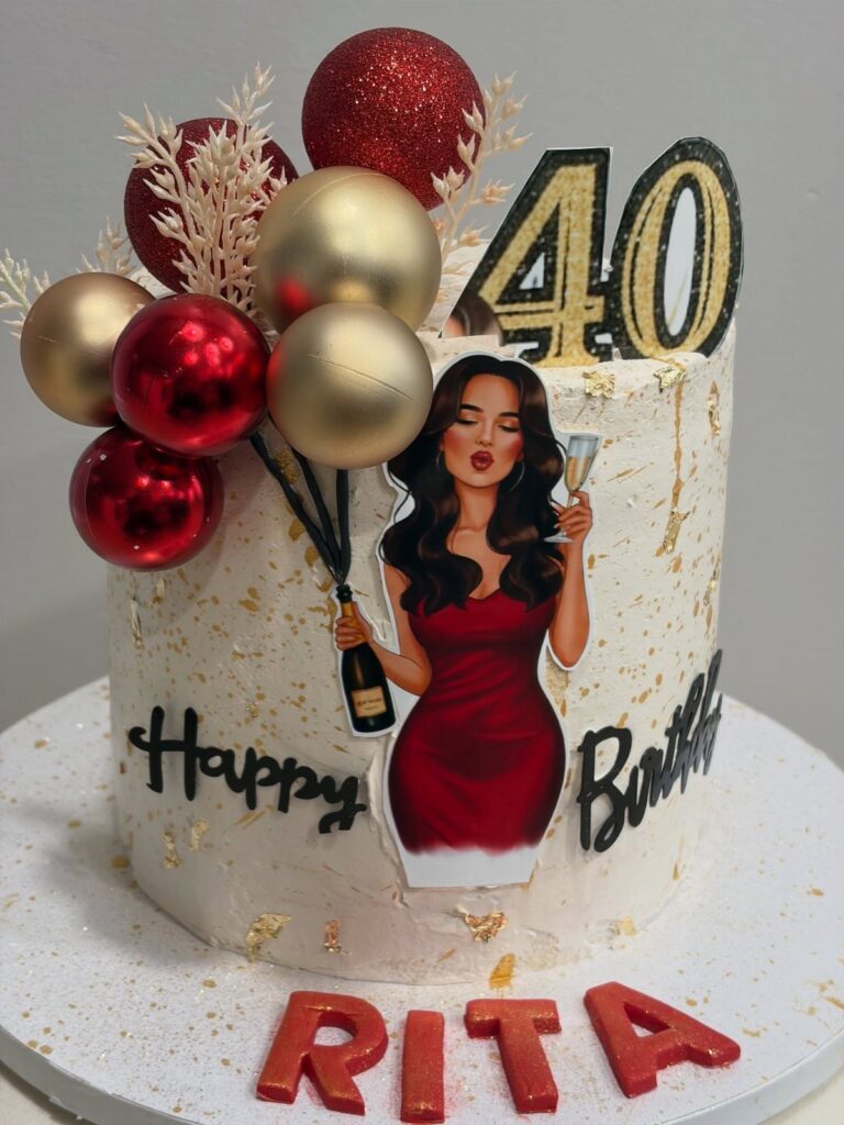 White birthday cake with gold flakes, red baubles, and a 40 topper.