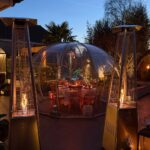 Dining dome on a patio with set table and two pyramid patio heaters.