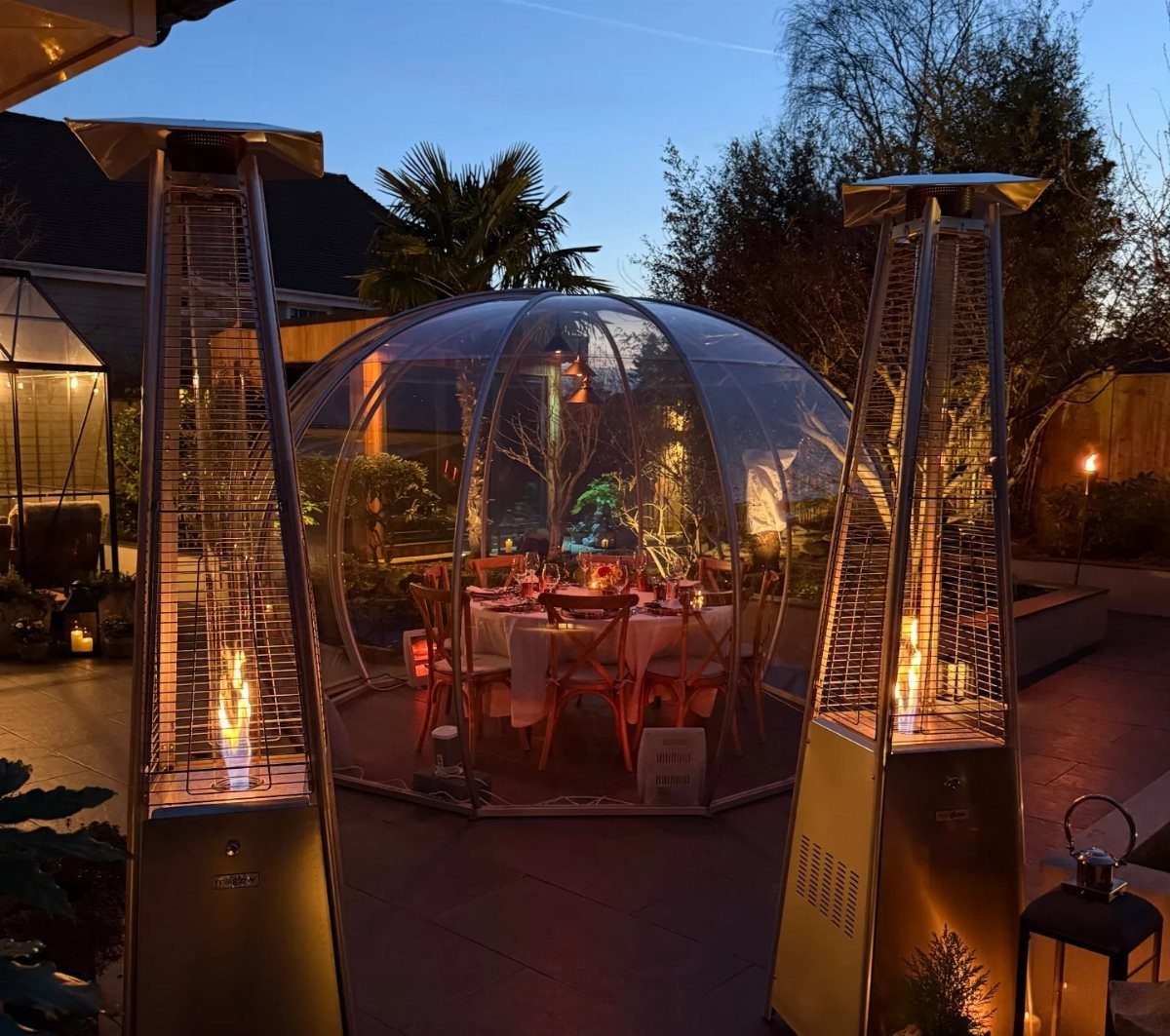Dining dome on a patio with set table and two pyramid patio heaters.